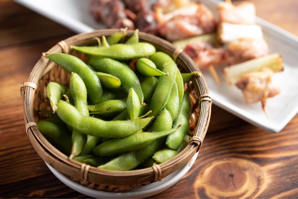 a bowl of edamame and skewers 