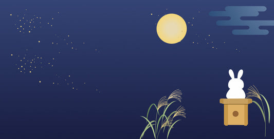 An illustration of a rabbit pounding mochi on a wooden pedestal under the full moon, surrounded by Japanese pampas grass and a starry night sky.