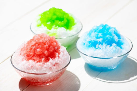 Three bowls of colorful shaved ice, featuring red, green, and blue flavors, served in glass bowls.